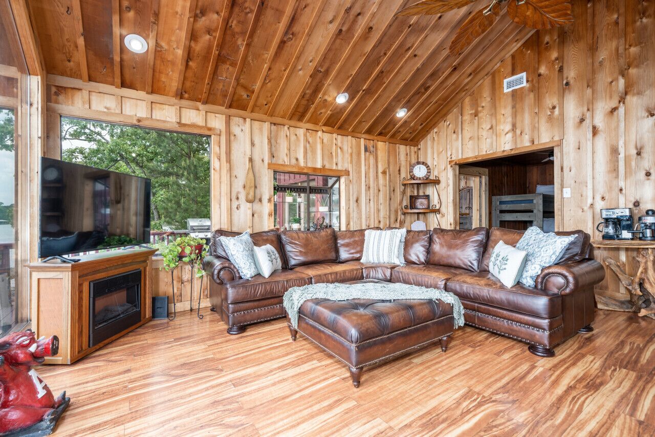 Un interior de madera con un sofá seccional de cuero, un televisor y una chimenea.