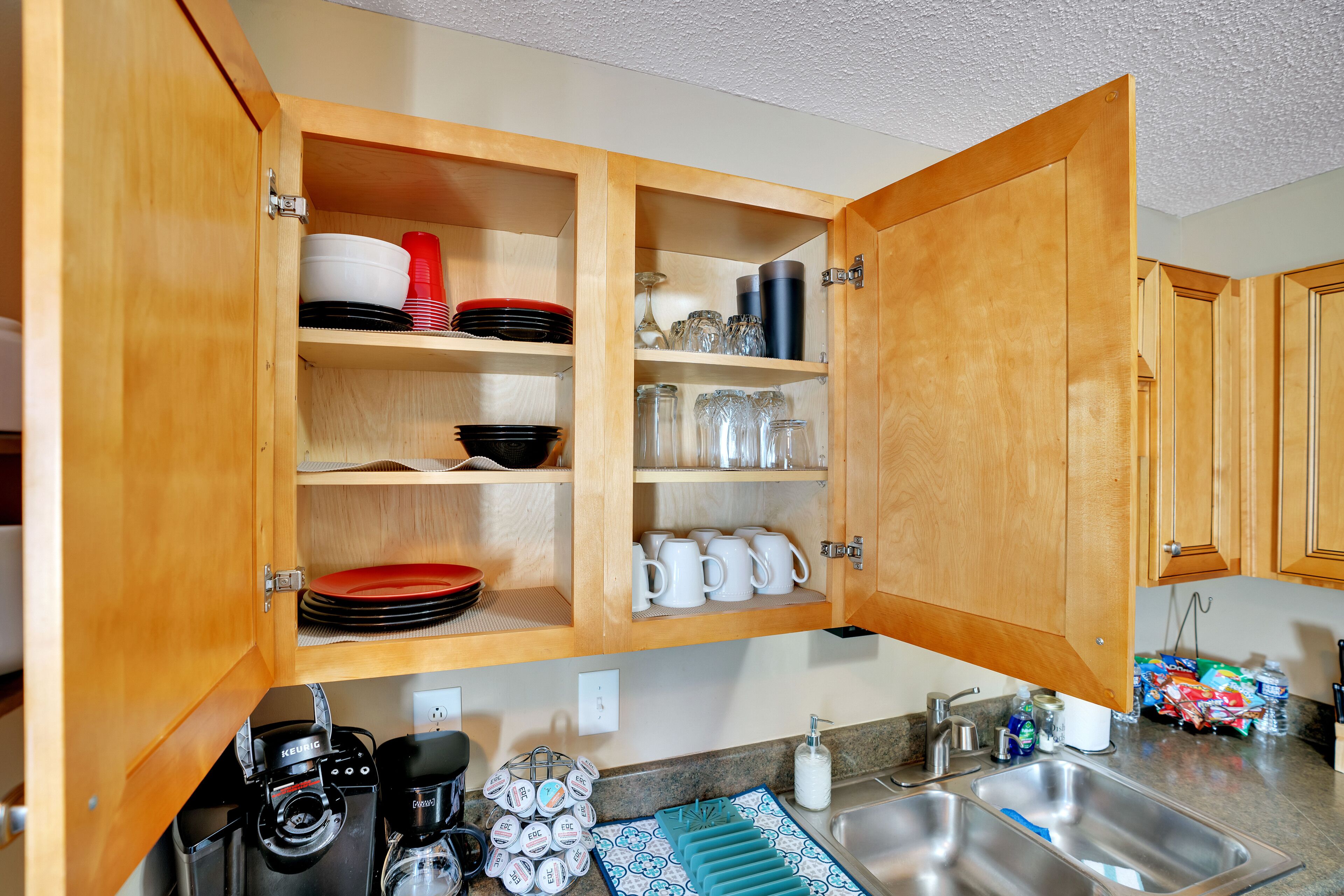 A kitchen with wooden cabinets, a coffee maker, and various dishes and utensils.