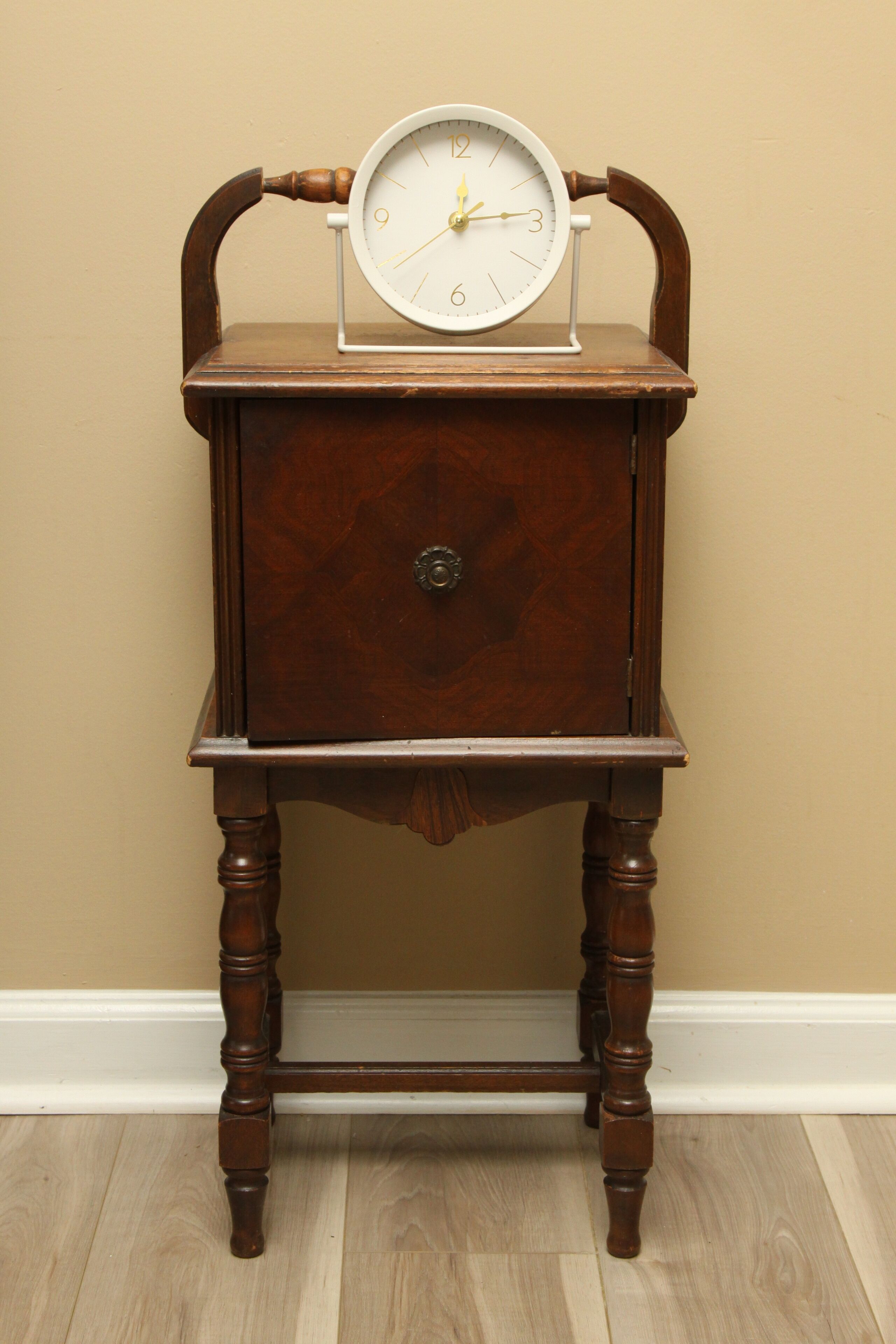 A wooden bedside table with a round clock.