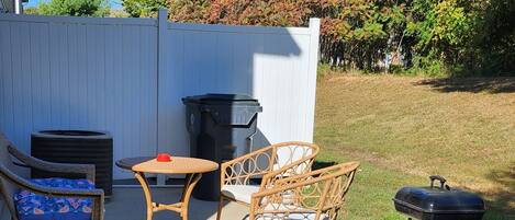 A patio with wicker furniture, a small round table, and a grill.