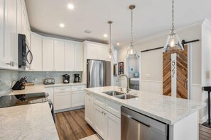 A modern kitchen with white cabinets, stainless steel appliances, and pendant lighting. - Southernmost View - Private Pool (Key West)