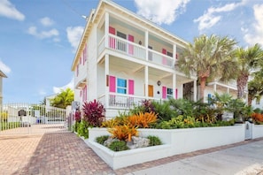 Un immeuble à deux étages doté de balcons, d’une entrée sécurisée et d’un aménagement paysager de style tropical.