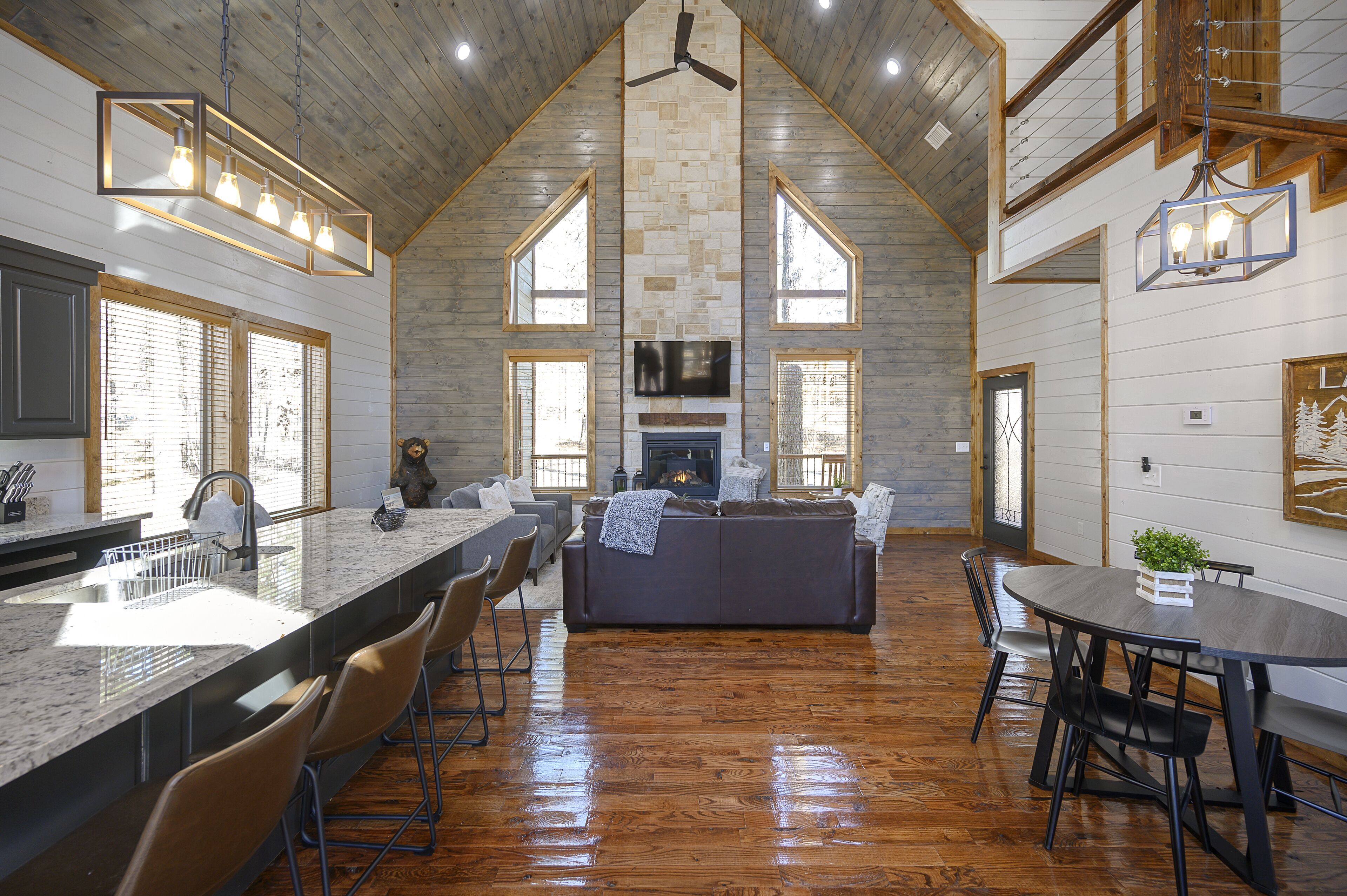 A spacious kitchen with a long island, a fireplace, and a dining area with a round table and chairs.