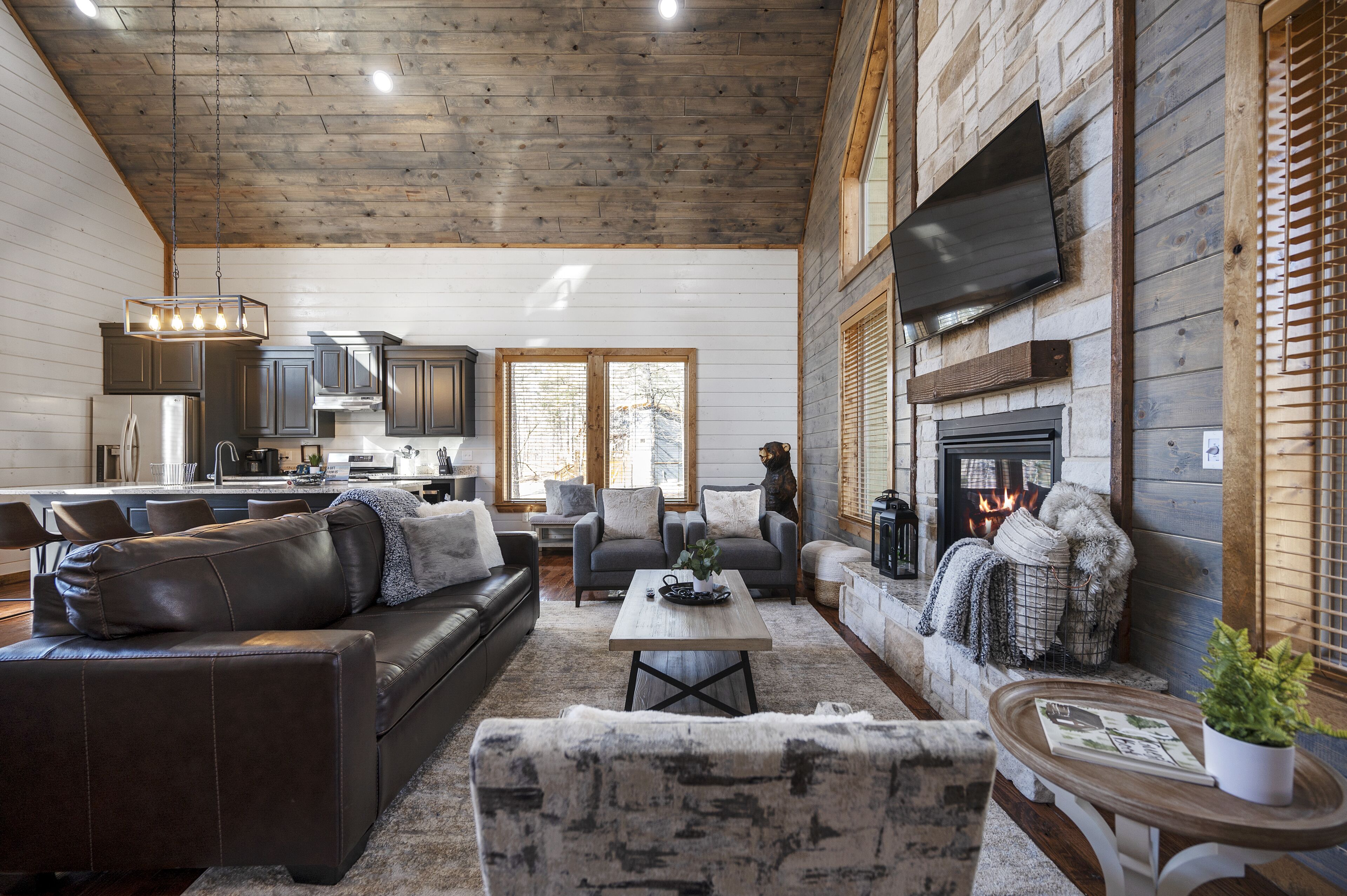 A spacious living area with a fireplace, leather sofas, and a wooden ceiling.