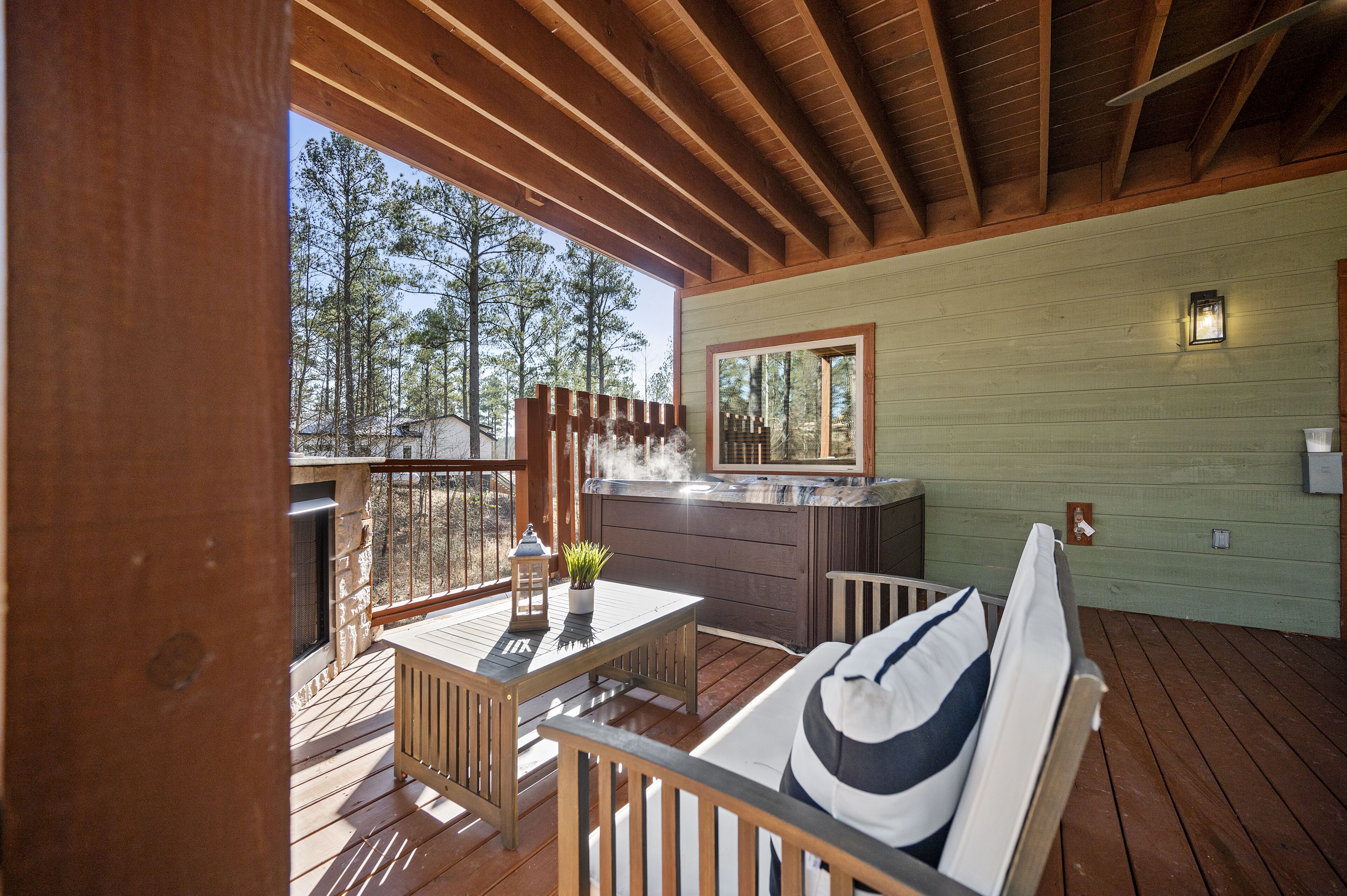 Una terraza de madera con una mesa y sillas, un jacuzzi y vistas a árboles.