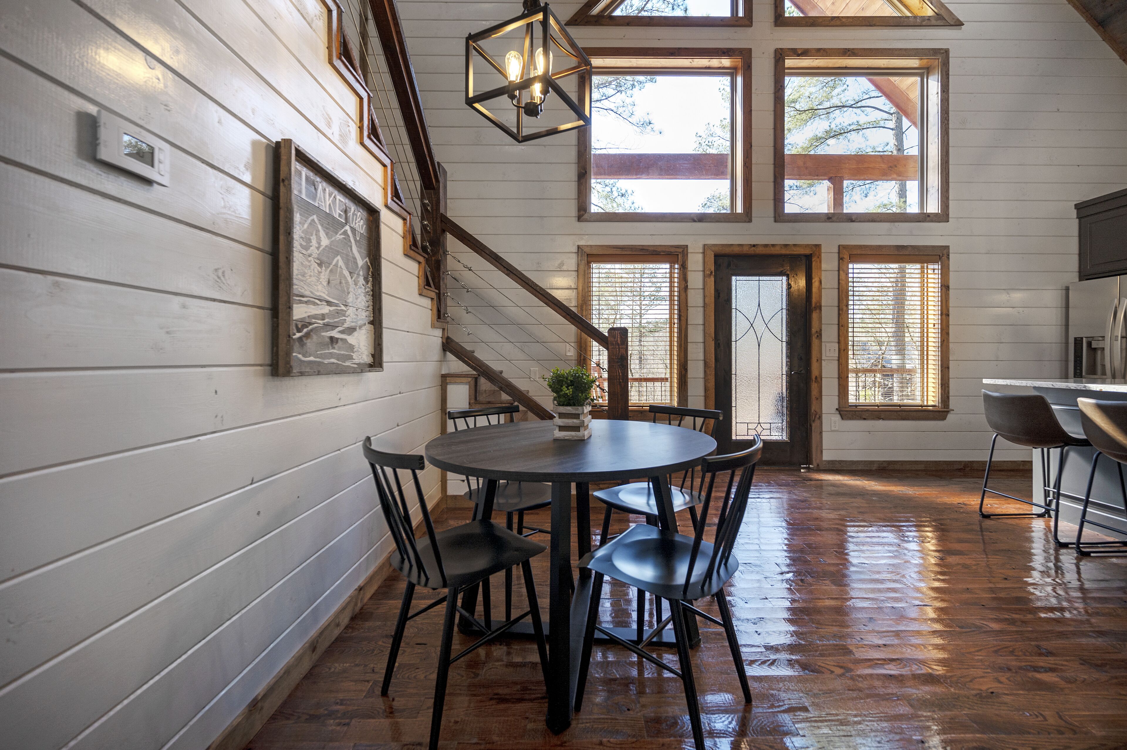 A wooden interior with a dining table, chairs, and a staircase.