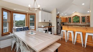 A modern kitchen with a large island, white cabinetry, and a view of the outdoors. - Z's By The Sea: Private Pool | Hot Tub | Rec Room (Kitty Hawk)
