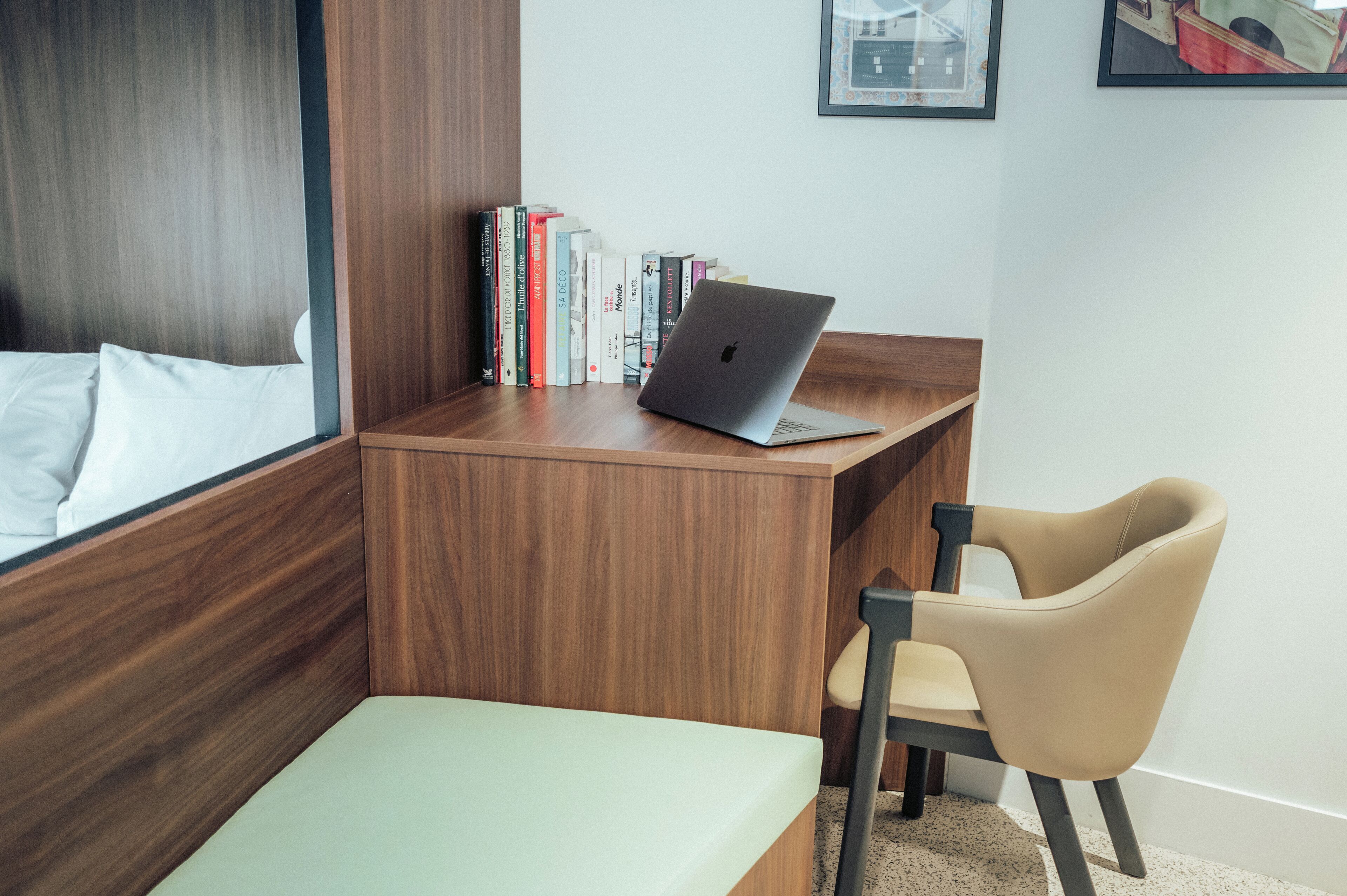Een moderne kamer met een houten bureau, een laptop, een stoel en een boekenkast vol boeken.