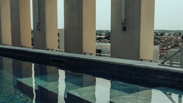 Une piscine moderne à l’eau claire, entourée de piliers en béton et dotée d’un sol carrelé.