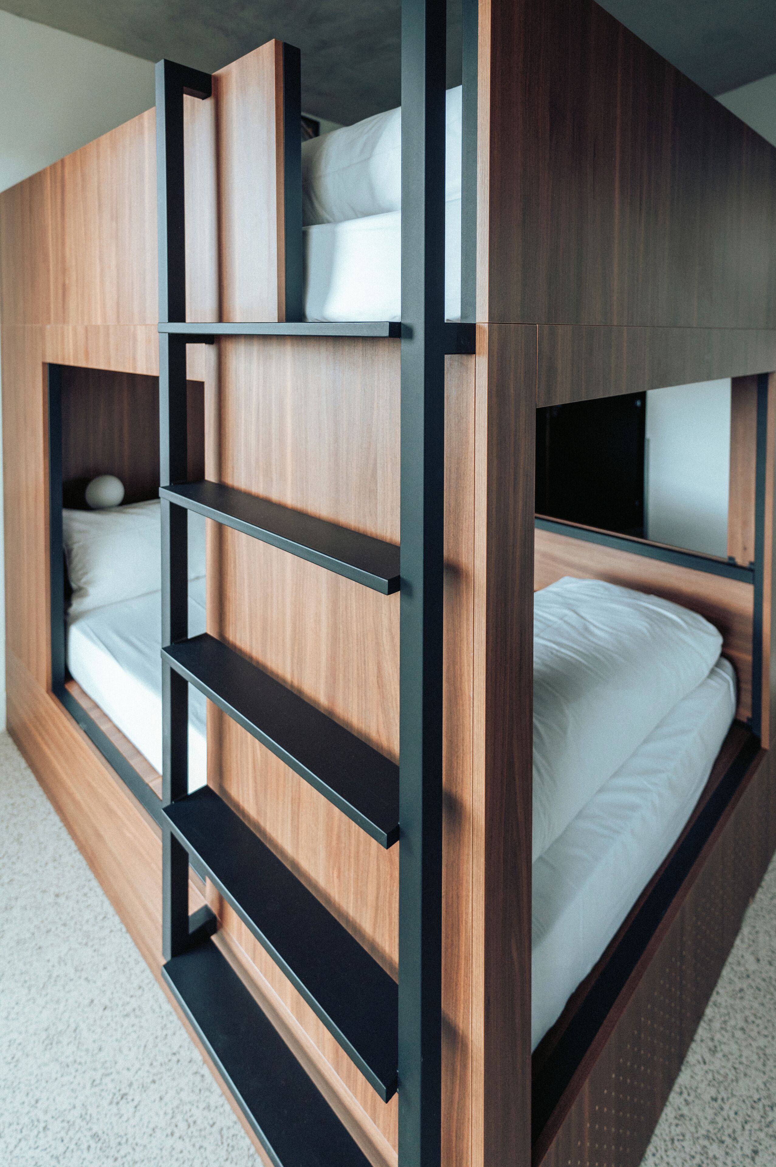 Una cama litera con estructura de madera y estantes de metal negro.