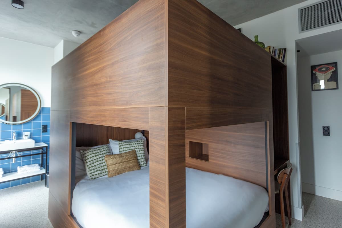Une chambre à coucher moderne avec un lit intégré, une salle de bain avec un mur recouvert de carreaux bleus et un miroir.