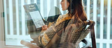 A person sitting on a rocking chair by a window with a book.