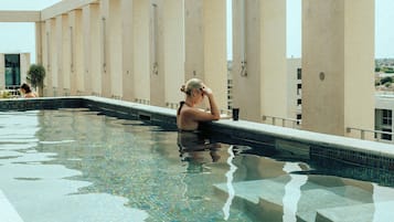 Une piscine dont le fond est carrelé, avec une personne assise au bord.