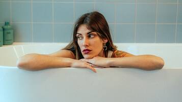 Una persona appoggiata a una vasca da bagno in un bagno con piastrelle blu.