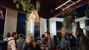 An indoor social gathering with people seated at tables, a hanging light fixture, and potted plants. - JOST Hôtel Bordeaux Centre Gare Saint Jean (Bordeaux)