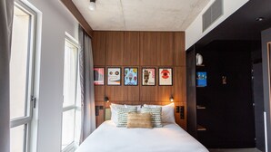 A bedroom with a bed, a wooden headboard, and a wall with framed artwork. - JOST Hôtel Bordeaux Centre Gare Saint Jean (Bordeaux)