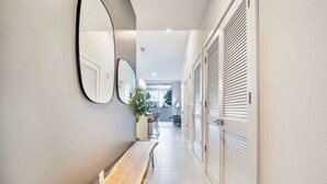 A hallway with a bench, a mirror, and a door with louvered shutters. - Brand New Cool 1 Bdrm Condo In Best Miami Location (Miami)
