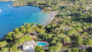 An aerial view of a coastal property with a swimming pool, surrounded by lush greenery and a beach. - Villa Ottagonale, Capo Perla (Capoliveri)