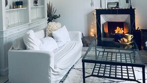 Una sala moderna con un sofá blanco, una mesa de centro de vidrio, una chimenea y una estantería.