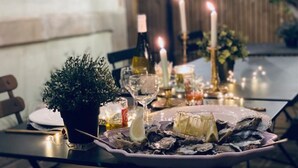 Una mesa de comedor dispuesta con ostras, velas y una planta en maceta.