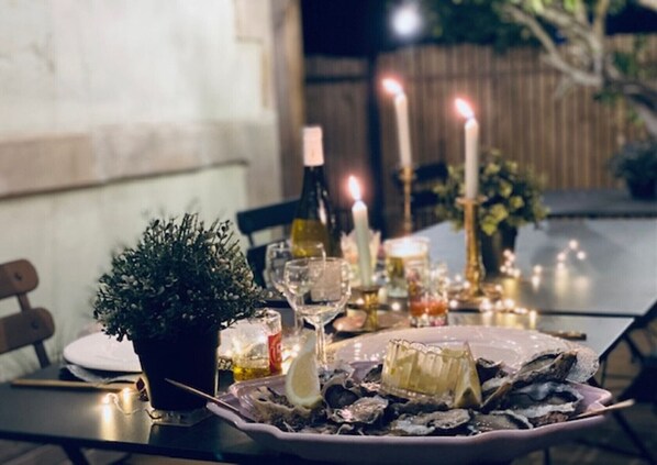 Ruokapöytä on katettu osterien, kynttilöiden ja ruukussa kasvavan kasvin kanssa.