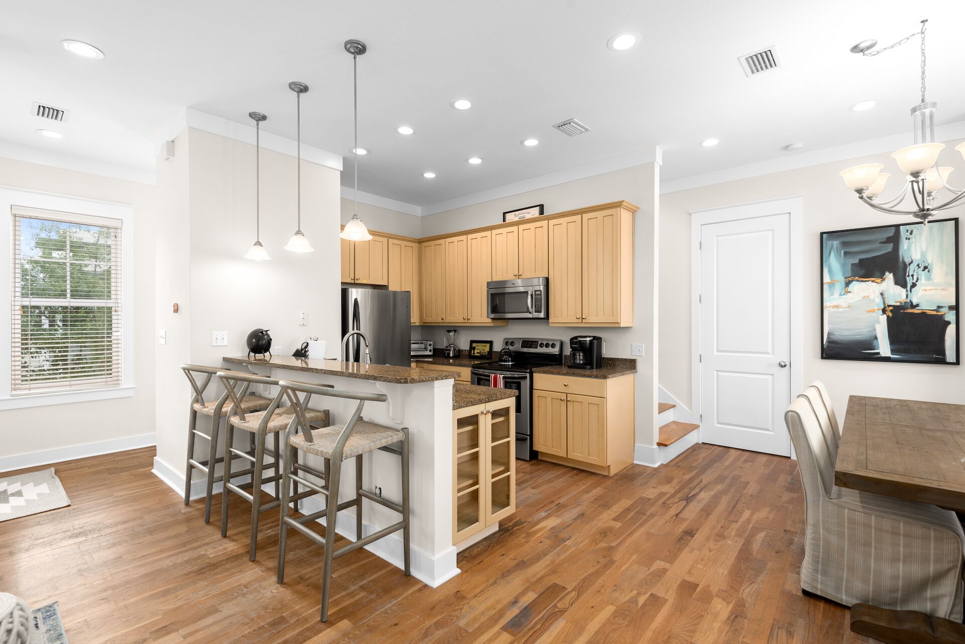 A modern kitchen with wooden cabinets, stainless steel appliances, and a central island with bar stools.