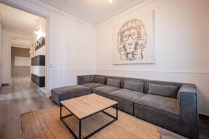 A modern living room with a sectional sofa, a wooden coffee table, and a large abstract artwork on the wall. - Sweett | Rocafort 402 (Barcelona)
