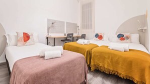 Hotellihuone, jossa on kaksi sänkyä, työpöytä ja tuoli.