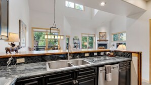 A kitchen with a granite countertop, black cabinets, a double sink, and a hanging light fixture. - Stunning 3-Bedroom Top Floor Condo – Walk to Lifts and Downtown (Breckenridge)