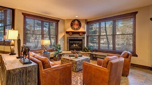 A spacious living room with leather sofas, a fireplace, and large windows with blinds. - Stunning 3-Bedroom Top Floor Condo – Walk to Lifts and Downtown (Breckenridge)