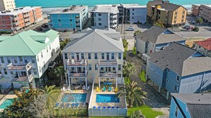 Un hotel de varios pisos con zona de piscina, balcones y vistas al océano.