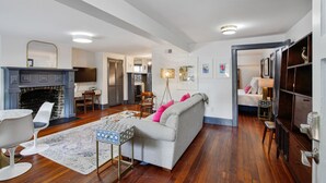 A spacious living room with a fireplace, a sofa, a coffee table, and a dining area. - Ground Level Apartment in City Center by Perry Lane Hotel (Savannah)