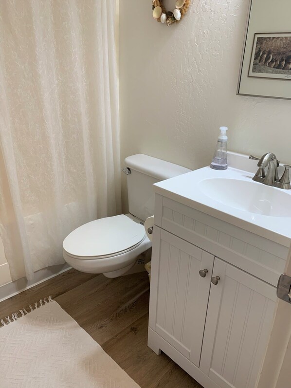 A bathroom with a toilet, sink, and cabinet.