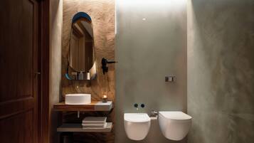 Un baño moderno con tocador de madera, un espejo grande, dos inodoros y un pequeño cubo de basura.