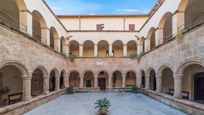A courtyard with multiple arches, stone walls, and potted plants. - San Francesco Heritage Hotel (Alghero)