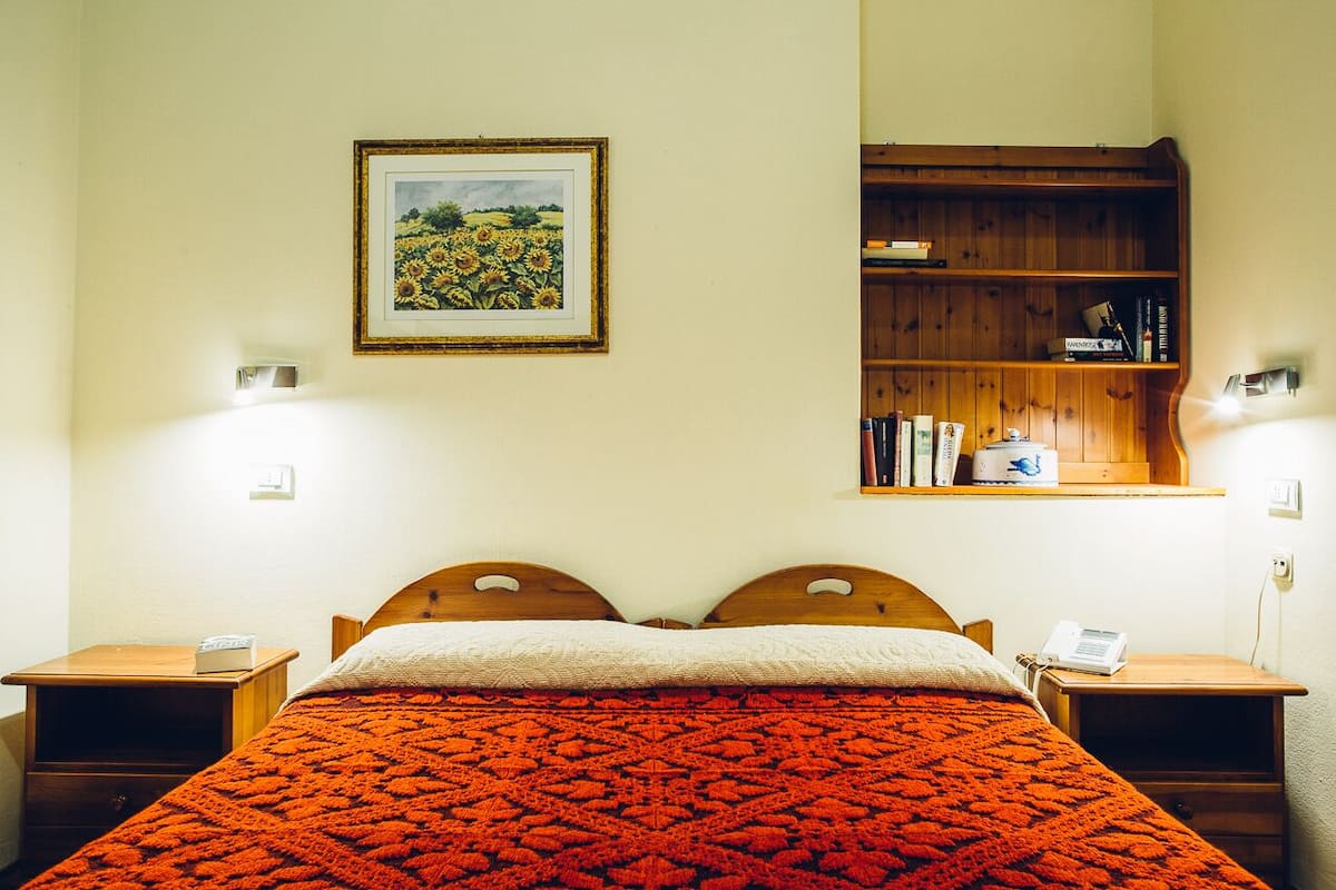 A bedroom with a wooden bed, a bookshelf, and a framed picture on the wall.