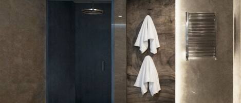 A modern bathroom with a walk-in shower, a towel rack with two towels, and a built-in towel warmer.