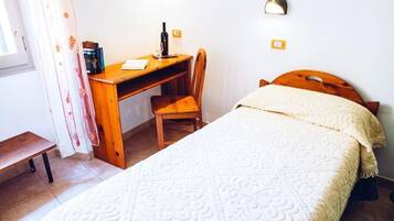 Une chambre à coucher avec un lit, un bureau en bois, une chaise et une table de chevet.