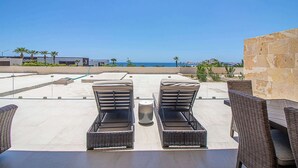 Una terrazza sul tetto con due poltrone, un tavolo e vista sull'oceano.