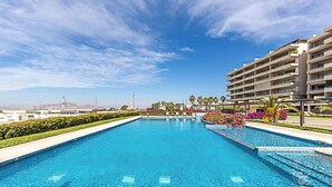 Una piscina rettangolare con acqua cristallina, circondata da un basso siepe e fiori colorati.