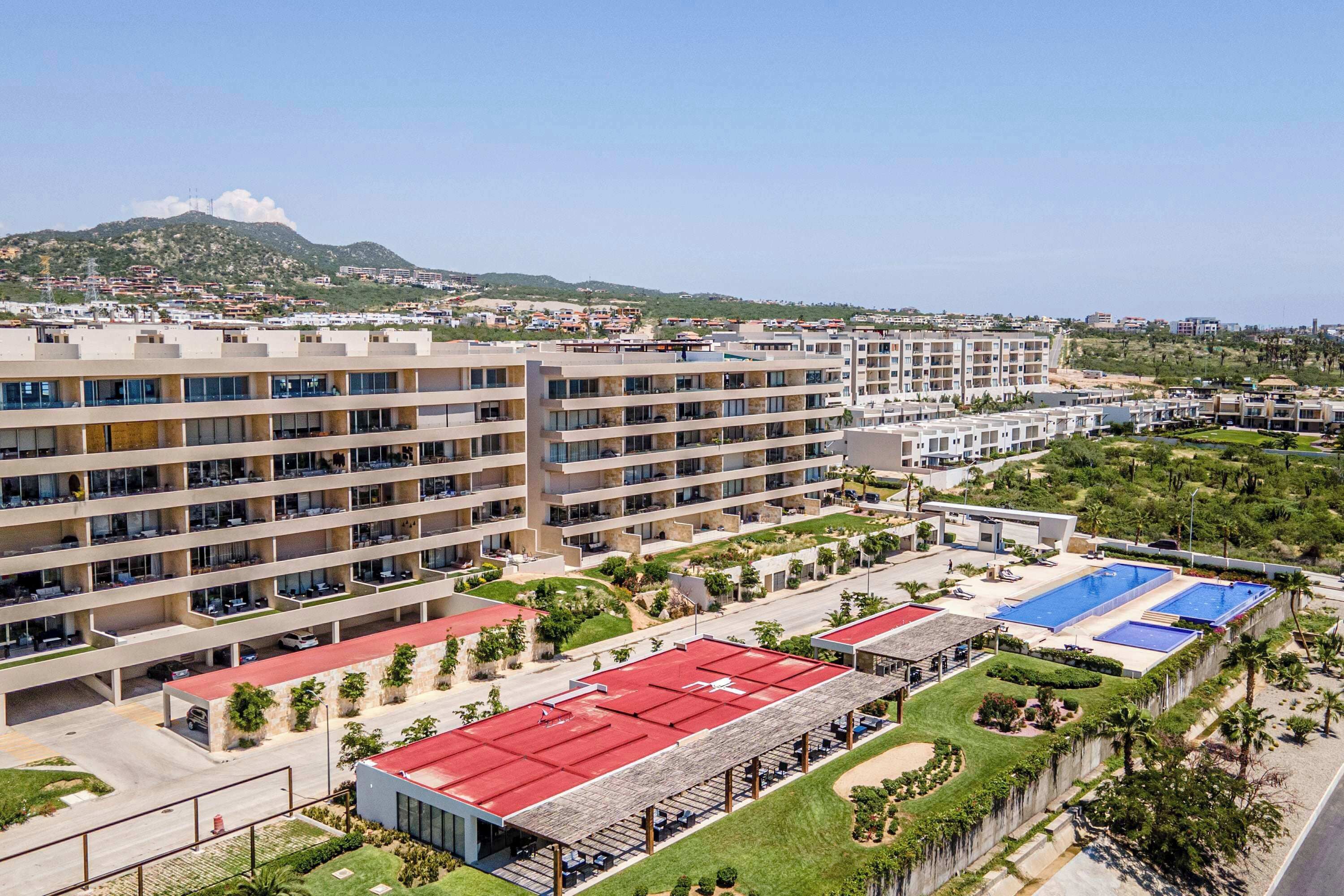 Um hotel com vários andares, área de piscina com telhado vermelho e vista para uma paisagem montanhosa ao fundo.