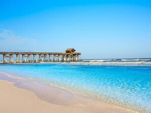 A pier extending into clear blue water with a sandy beach in the foreground. - Turtle Nest 3br with hot tub, great park, beach! (Satellite Beach)