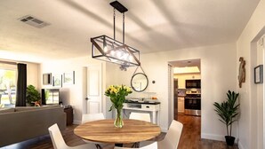 Un espace repas moderne avec une table ronde en bois, des chaises blanches et un luminaire suspendu.