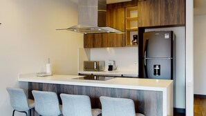 Une cuisine moderne dotée d’un îlot central, d’un four à micro-ondes encastré et d’un réfrigérateur à deux portes.