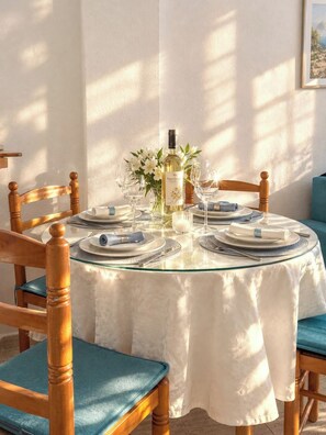A round dining table with a white tablecloth, surrounded by wooden chairs with teal cushions. - Godisa 18 Apartment Playa del Cura Torrevieja! (Torrevieja)