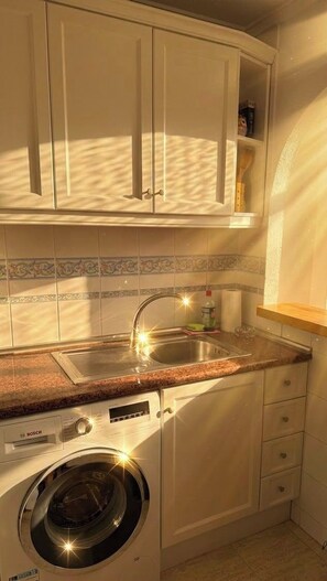A compact kitchen with a Bosch washing machine, a stainless steel sink, and a wooden countertop. - Godisa 18 Apartment Playa del Cura Torrevieja! (Torrevieja)