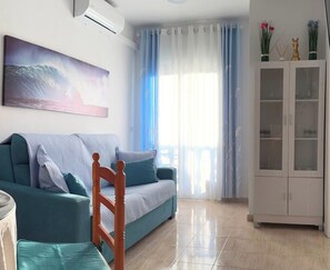 A living room with a sofa, a chair, a cabinet, and a painting on the wall. - Godisa 18 Apartment Playa del Cura Torrevieja! (Torrevieja)