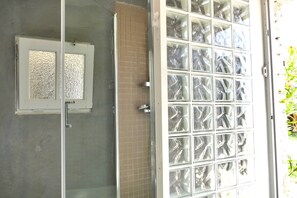Une salle de bain avec une douche à parois de verre, un mur carrelé et une porte en verre dépoli.