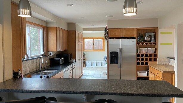 A modern kitchen with granite countertops, wooden cabinets, stainless steel appliances, and pendant lighting. - Spacious and comfortable 5 bed, hot tub, home theater, fireplaces (Boulder)