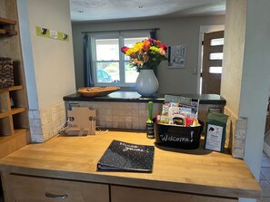 Una encimera de cocina con un jarrón de flores, un cartel de bienvenida y una bolsa de café.